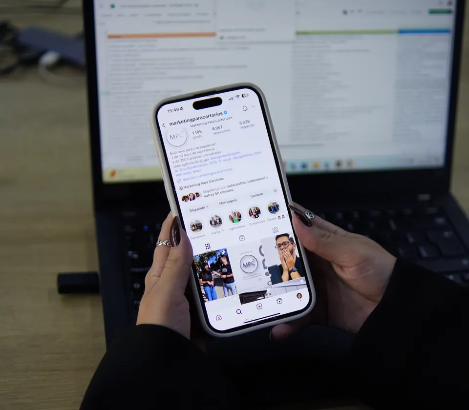 Celular com o Instagram de um cartório cliente aberto, em cima do notebook