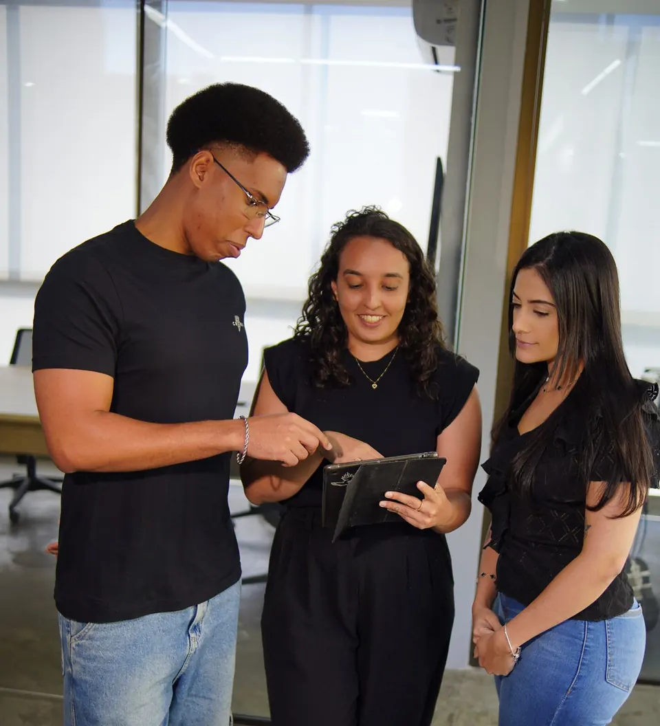 Três pessoas da equipe da MPC conferindo um trabalho num tablet, no escritório em Belo Horizonte