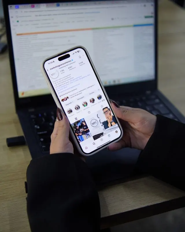 Celular mostrando o Instagram de um cliente, sobre um notebook